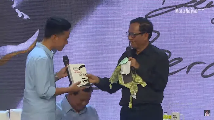 Cawapres dari pasangan nomor urut tiga Mahfud MD, memberikan sebuah buku biografi kepada&nbsp;cawapres dari kandidat lain,&nbsp;Gibran&nbsp;Rakabuming.