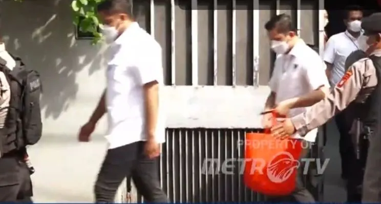 Tim penyidik keluar dari kediaman Firli dengan membawa sebuah koper berwarna abu-abu dan juga sebuah tote bag berwarna orang yang diduga berisi barang bukti.