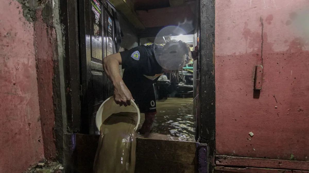 Warga merapikan barang-barang di dalam rumahnya di kawasan Gang Apandi, Kelurahan Braga, Kecamatan Sumur Bandung, Kota Bandung, Kamis 11 Januari 2023. Banjir yang menggenangi pemukiman warga tersebut terjadi disebabkan oleh  jebolnya tanggul sungai Cikapundung. (Ayobandung.com/Magang Foto/Ilham Ahmad Nazar)