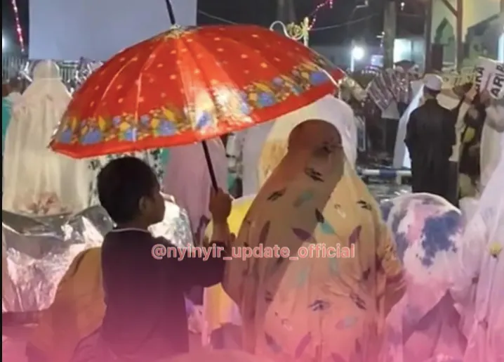 Viral Seorang Ibu Tarawih hingga Kehujanan, Sang Anak Sigap Payungi hingga Tuai Pujian