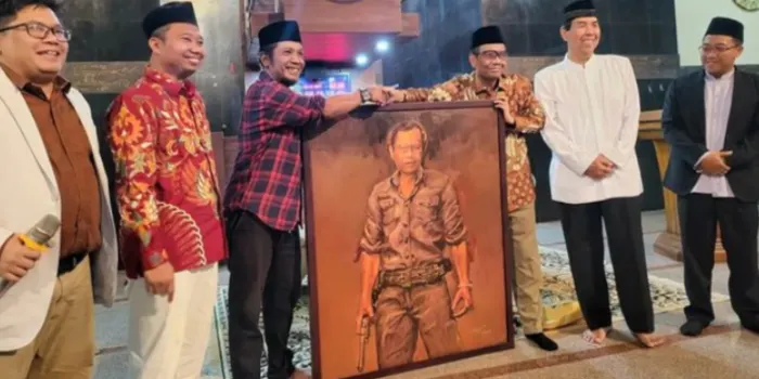 Profesor Mahfud MD saat menerima lukisan karya Perupa Wuri Hantoro berpakaian flanel merah di Kampus UIN Sunan Kalijaga .