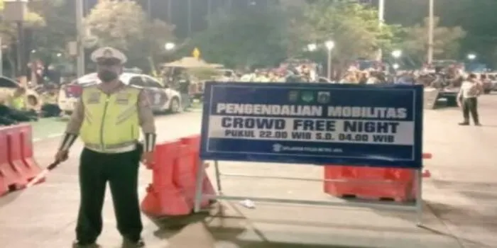 Ilustrasi. Seorang anggota polisi tengah berjaga di depan papan petunjuk penerapan crowd free night di Jakarta.