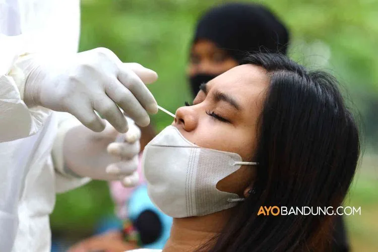 Petugas medis melakukan tes antigen kepada pengunjung objek wisata di Bandung.