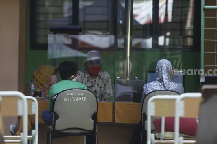 Petugas melayani orang tua siswa dan calon siswa di posko Penerimaan Peserta Didik Baru (PPDB) di SMK Negeri 15, Jakarta, Kamis (25/6). [Suara.com/Angga Budhiyanto]