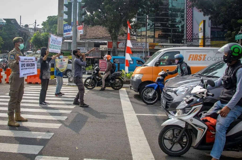 Satpol-PP Kota Bogor bersama musisi jalanan saat melakukan sosialisasi protokol kesehatan di simpang lampu merah Jambu Dua