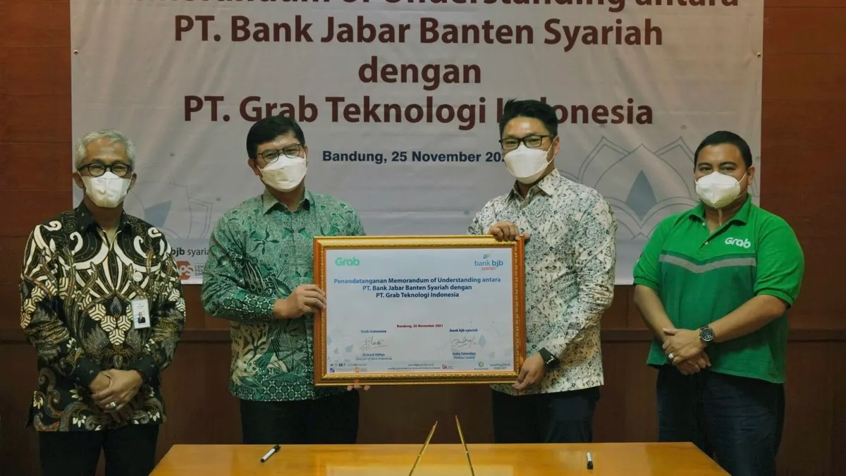 Richard Aditya, Director of West Indonesia, Grab Indonesia (kedua kanan) bersama Yose Tireza Arizal, Region Head of West Java & Central Java, Grab Indonesia (kanan pertama) saat menyerahkan bukti Penandatangan Nota Kesepahaman kepada Indra Falatehan, Direktur Utama Bank BJB Syariah (kiri kedua) yang didampingi oleh Vicky Fitriadi, Direktur Operasional Bank BJB Syariah (kiri pertama)