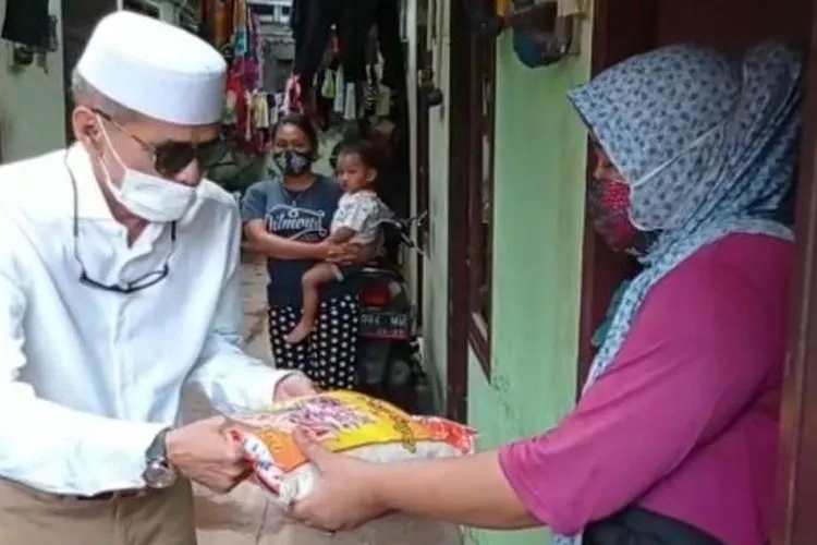 Habib Hasan Mulachela membagikan beras kepada warga warga di Kelurahan Semper Barat, Kecamatan Cilincing, Jakarta Utara, Kamis (4/2/2021).[Suara.com/ist]