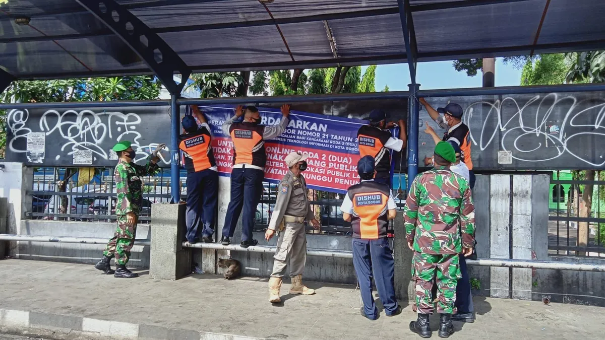 Petugas gabungan saat memasang banner sosialisasi kawasan bebas Ojol.