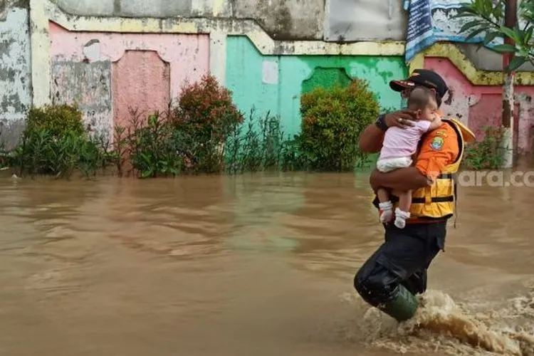 Personel BPBD Kota Bekasi mengevakuasi balita yang terdampak banjir karena tanggul Kali Bekasi di Perumahan PGP jebol, Jumat (19/2/2021).[Suara/com/Imam Faishal]