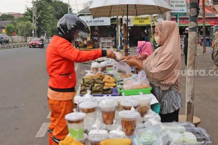 Pembeli memilih takjil untuk buka puasa di Jalan Panjang, Kebon Jeruk, Jakarta barat, Jumat (1/5). [Suara.com/Alfian Winanto]
