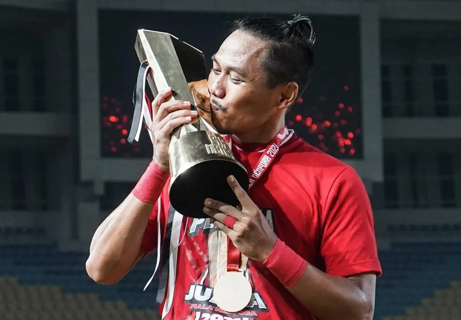 Tony Sucipto mencium sebuah tropi juara yang diraih Persija Jakarta.