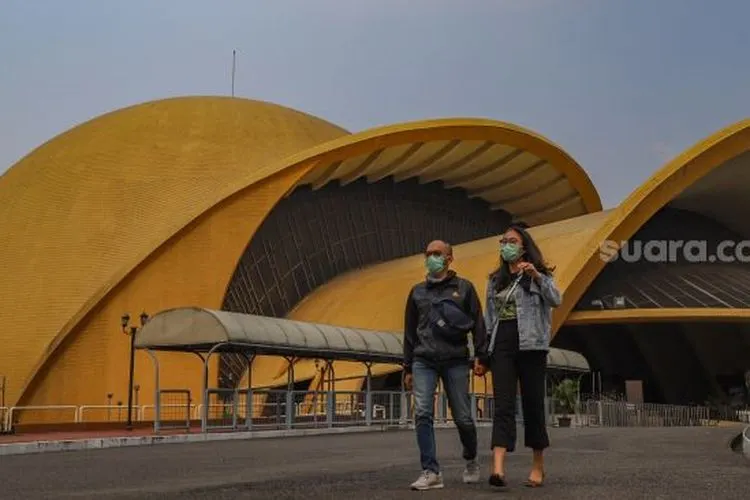 Sepasang kekasih melintas di depan Teater Keong Mas di Taman Mini Indonesia Indah, Jakarta Timur, Minggu (13/9). [Suara.com/Alfian Winanto]