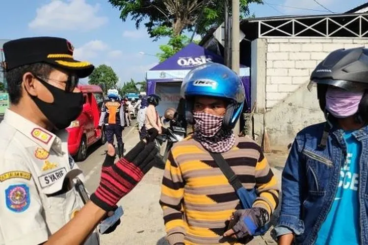 Petugas saat mengecek SIKM warga yang hendak masuk wilayah Jakarta, di check point Pasar Rebo, Rabu (3/6/2020). (Suara.com/Bagaskara Isdiansyah)