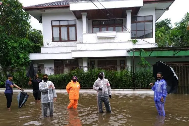 Petugas memantau banjir yang terjadi di jalan di depan rumah Kapolri Listyo Sigit Prabowo di Kelurahan Bangka, Kecamatan Mampang Prapatan, Jakarta Selatan, Kamis (18/2) siang.
