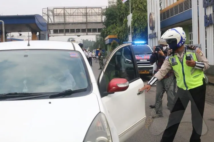 Polisi melakukan pengecekan terhadap pengendara yang keluar tol seiring pemberlakuan Pembatasan Sosial Berskala Besar (PSBB) di Kota Bekasi, Rabu (15/4/2020). (Ayobekasi.net/Firda Puri Agustine)
