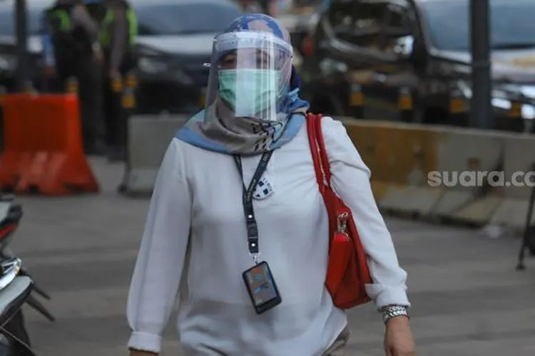Seorang pekerja kantor menggunakan face shield dan masker saat melintas di Kawasan Sudirman, Jakarta Pusat, Senin (8/6). [Suara.com/Alfian Winanto]