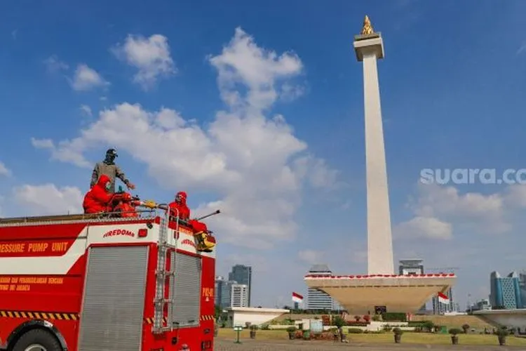Petugas Pemadam Kebakaran menyemprotkan cairan disinfektan di Kawasan Monumen Nasional (Monas), Jakarta Pusat, Rabu (17/6/2020). (Suara.com/Alfian Winanto)