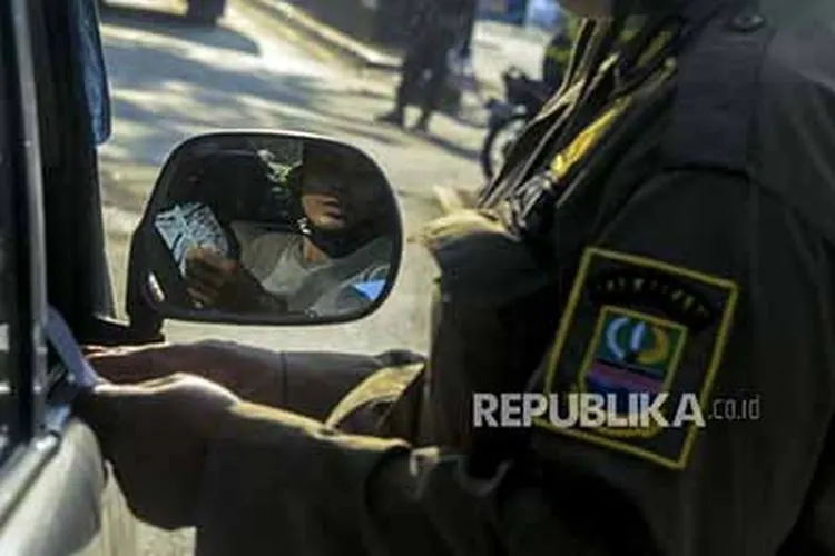 Petugas Satpol PP saat memeriksa dokumen pengendara yang akan memasuki wilayah DKI Jakarta di perbatasan Bekasi-Karawang, Jawa Barat, Jumat (29/5). Penyekatan kendaraan pemudik itu untuk mencegah kembalinya pemudik yang akan kembali ke Jakarta tanpa membawa Surat Izin Keluar Masuk (SIKM) guna mengatasi penyebaran virus Corona  (Foto: Republika/Putra M. Akbar)