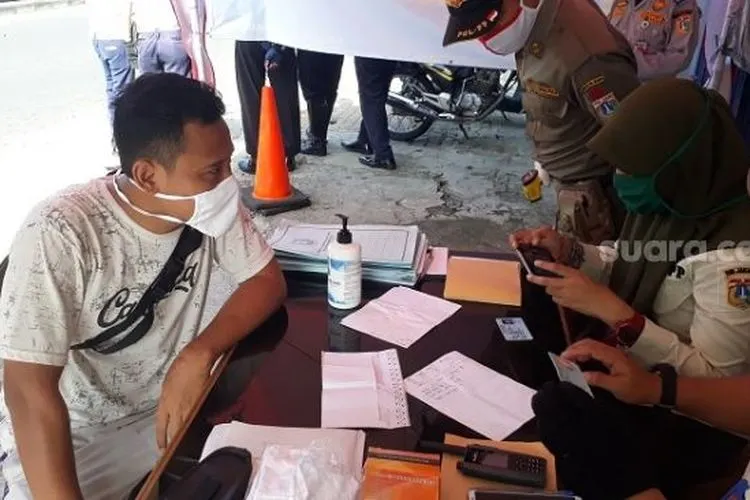Pelanggar PSBB yang dikenakan sanksi sosial oleh petugas di check point Pasar Rebo, Jaktim. (Suara.com/Bagaskara).