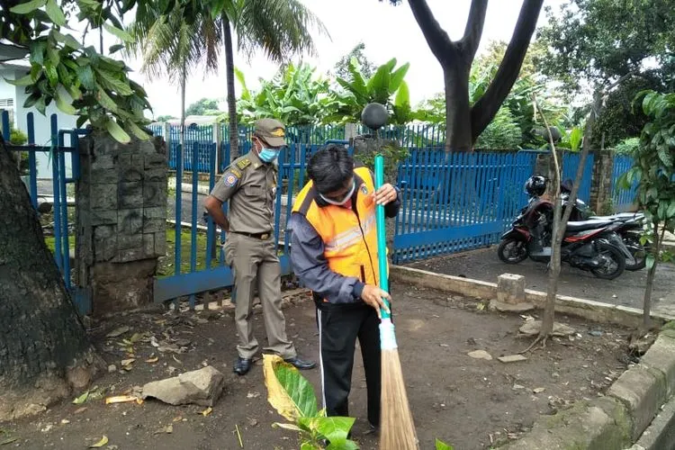Warga yang ketahuan tidak memakai masker dipaksa menyapu jalan setelah terciduk razia PSBB saat melintas di Jalan Raya Bogor, Kelurahan Rambutan, Ciracas. (Dok. Kelurahan Rambutan)