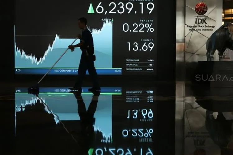 Karyawan melintas di dekat monitor pergerakan harga saham di Gedung Bursa Efek Indonesia, Jakarta, Rabu (23/10). [Suara.com/Arya Manggala]