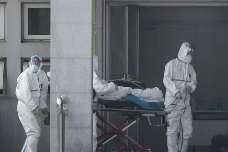 Staf medis membawa seorang pasien yang terinfeksi virus korona ke rumah sakit Jinyintan, di Wuhan (EPA)