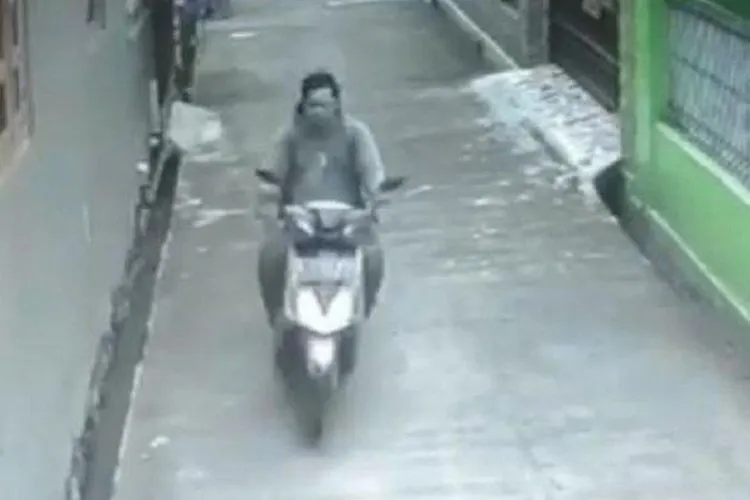 Pelaku yang mengendarai motor terekam CCTV saat melakukan pelecehan seksual terhadap seorang perempuan berkerudung panjang yang sedang berjalan kaki. (Instagram/Tribunnews)