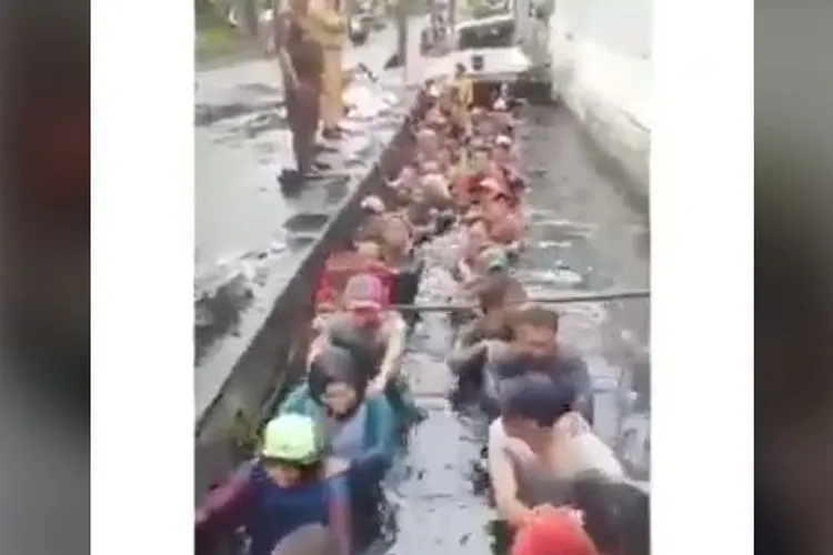 Tangkapan layar dari video yang merekam kegiatan para pegawai honorer DKI masuk ke selokan kotor di bawah pengawasan beberapa orang berpakaian PNS di kawasan Jelambar, Jakarta Barat.