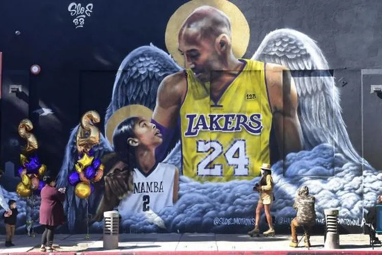 Sejumlah penggemar berkumpul di dekat sebuah mural dari mendiang pemain bola basket profesional NBA Kobe Bryant dan mendiang putrinya Gianna di pusat Kota Los Angeles, California, Amerika Serikat, Selasa (26/1/2021). [Frederic J. BROWN / AFP]