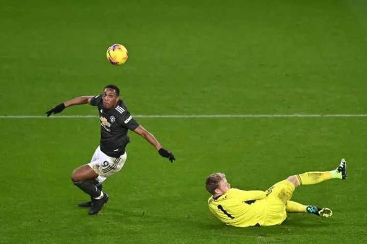 Penyerang Manchester United Anthony Martial (kiri) menaklukan kiper Aaron Ramsdale sebelum merobek gawang Sheffiled United dalam laga pekan ke-13 Liga Inggris di stadion Bramall Lane, Jumat (18/12/2020) dini hari WIB. [Laurence Griffiths / POOL / AFP]