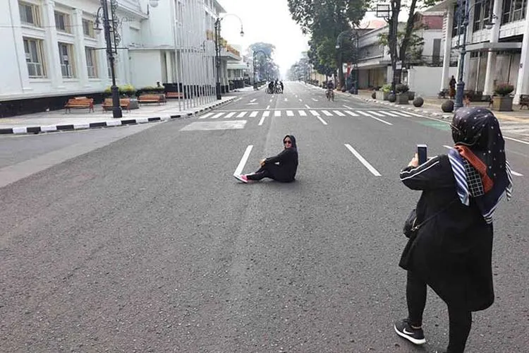 Sejumlah warga beraktivitas di Jalan Asia-Afrika yang ditutup untuk pembatasan sosial dan pengurangan titik kumpul warga guna mencegah penyebaran Covid-19 di Kota Bandung, Kamis (16/4/2020). (Ayobandung.com/Irfan Al-Faritsi)