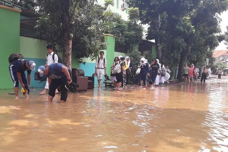 Murid SMAN 8 terpaksa pulang dengan menenteng sepatu akibat banjir yang merendam kawasan gedung sekolah mereka pada April 2019). (Kompas.com/Ardito Ramadhan)