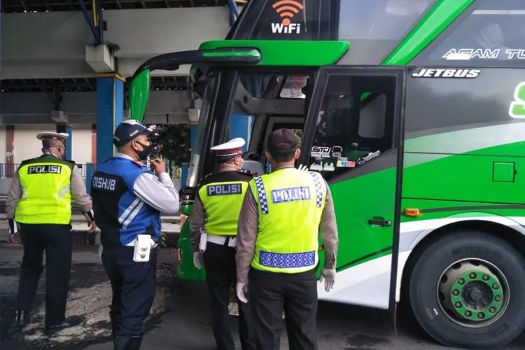 Petugas gabungan menghentikan bus saat hendak masuk ke Semarang di perbatasan di depan Terminal Mangkang, Senin (27/4/2020). (dok)