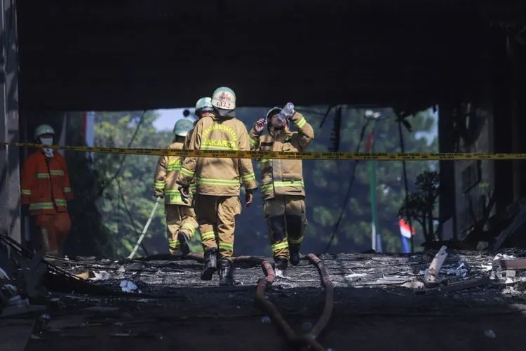Petugas Damkar DKI berjalan keluar usai melakukan proses pendinginan di Gedung Utama Kejaksaan Agung RI di Jalan Sultan Hasanuddin, Jakarta Selatan, Minggu (23/8). [Suara.com/Alfian Winanto]