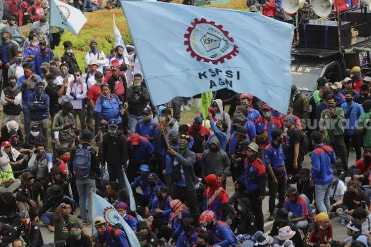 Massa aksi yang tergabung dalam elemen buruh mengibarkan bendera saat berunjuk rasa di kawasan Patung Kuda Arjuna Wiwaha, Jakarta, Kamis (22/10/2020). [Suara.com/Angga Budhiyanto]
