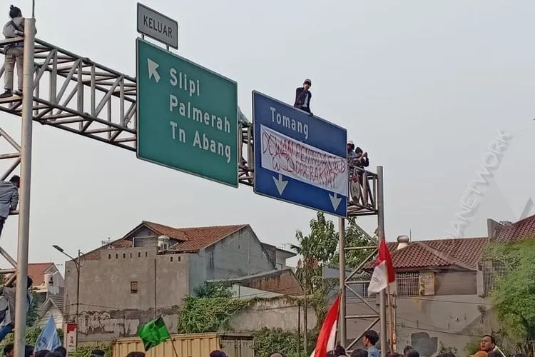 Sejumlah mahasiswa memanjat papan penunjuk jalan di tengah tol dalam kota seberang gedung DPR, Senayan, Jakarta Pusat dan memasang spanduk protes/Ayojakarta.com