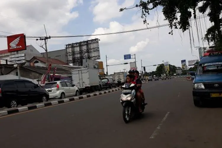 Pengendara motor di PSBB Depok berboncengan tiga, tanpa helm, dan tidak menggunakan masker. (Suara.com/Novian)