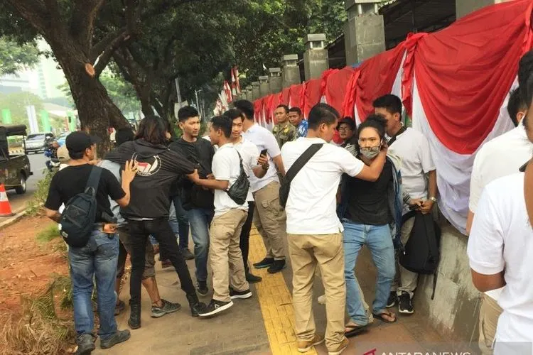 Polisi berkaos putih menggeledah paksa masa berkaos hitam yang diduga akan berdemo di depan gedung parlemen di Jakarta, Jumat (16/8/2019). (ANTARA/Galih Pradipta)