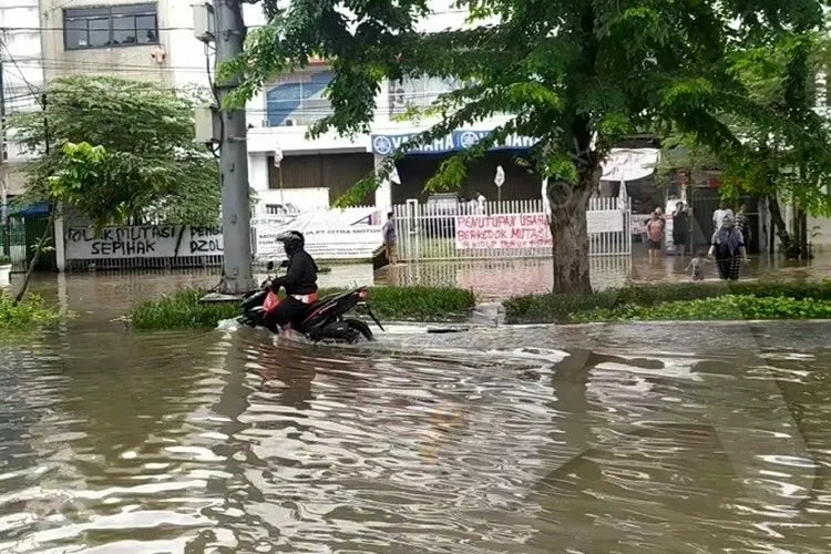 Pengendara motor menerjang banjir di Jalan Bungur Raya, Kemayoran, Jakarta Pusat pada Selasa (25/2/2020). (Ayojakarta.com/Khoirur Rozi)