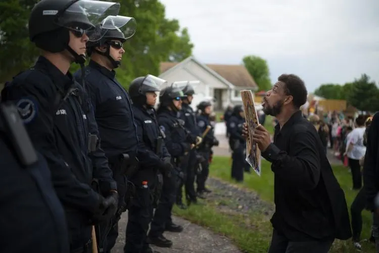 Seorang demonstran berhadapan dengan polisi di rumah petugas kepolisian Minneapolis Derek Chauvin yang dipecat pada Rabu (27/5/2020). (Jeff Wheeler / Star)