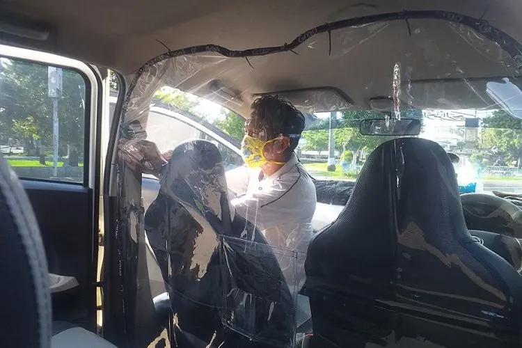 Pengemudi GrabCar tengah memasang pelindung plastik untuk mencegah dan melindungi penumpang dari virus korona, Rabu (29/4/2020).(Ayotegal.com/Lilisnawati)