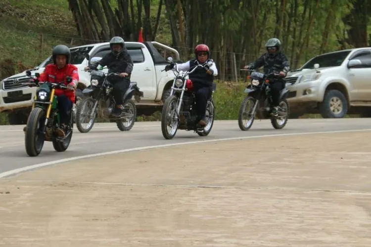 Presiden Joko Widodo mengendarai sepeda motor custom bersama Menteri Pekerjaan Umum dan Perumahan Rakyat (PUPR), Basuki Hadimuljono, saat kunjungan kerja di jalur perbatasan Indonesia-Malaysia. (Dok. Biro Komunikasi Publik PUPR)