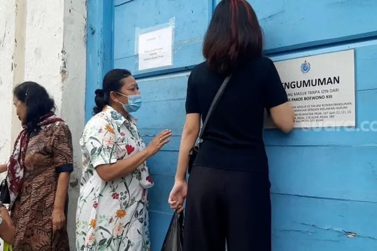Yemi, dan Kerabat Keraton lain saat mencoba mengetok pintu dari sasonoputro untuk masuk memberikan makan serta minum untuk kerabat yang terkurung di dalam, Jumat (12/2/2021). (suara.com)