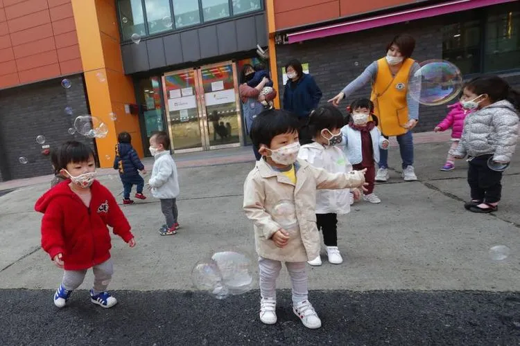 Anak-anak bermasker tengah bermain balon di Kuil Chogyesa di Korea Selatan, Jumat (24/4/2020). Pemerintah Korea Selatan merencanakan akan melakukan pengumuman untuk memulai mendatangkan kembali siswa ke sekolah paling lambat awal Mei. (AP Photo/Ahn Young-joon)