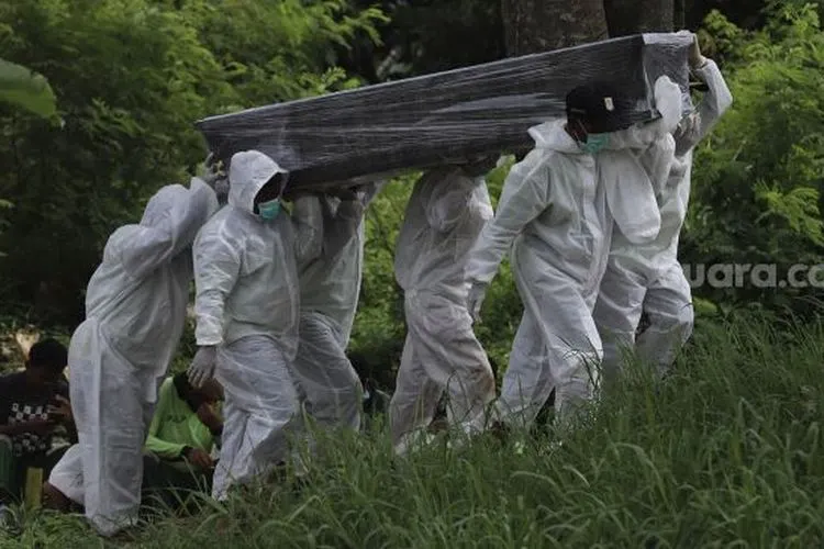 Petugas mengusung peti berisi jenazah yang meninggal dunia karena Covid-19 untuk dimakamkan di TPU Srengseng Sawah, Jakarta Selatan, Jumat (15/1/2021). [Suara.com/Angga Budhiyanto]