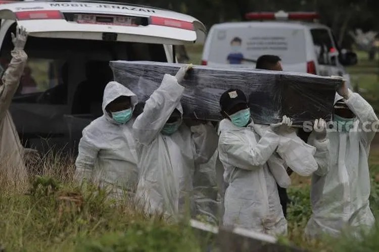 Petugas mengusung peti jenazah yang meninggal dunia karena Covid-19 untuk dimakamkan di TPU Srengseng Sawah, Jakarta, Jumat (15/1/2021). [Suara.com/Angga Budhiyanto]