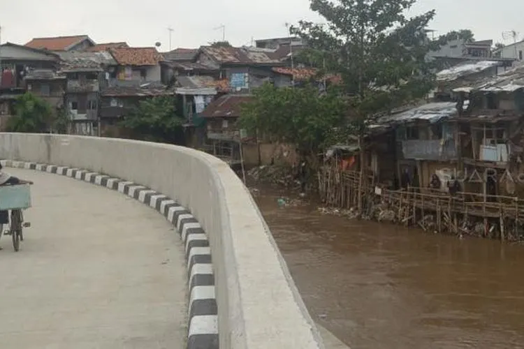 Warga melintas di samping Sungai Ciliwung, Jakarta, Rabu (19/9). [Suara.com/Muhaimin A Untung]