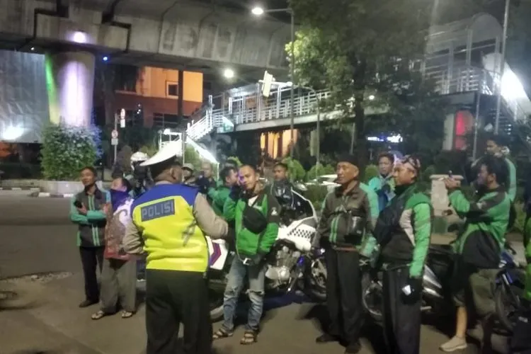 Foto yang diunggah akun Twitter TMC Polda Metro memperlihatkan anggota Polri memberikan imbauan kepada para pengemudi ojek online yang masih bergerombol di kawasan Blok M, Jakarta Selatan, untuk segera pulang ke rumah masing-masing, Sabtu (28/3/2020) dini hari.