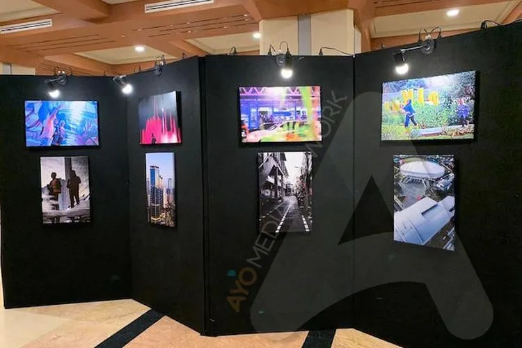 Pengunjung Balaikota, Aryadita, tampak serius menikmati sebuah foto karya George Timothy dalam pameran yang diselenggarakan sepanjang Jumat (6/12/2019). (Ayojakarta.com/Aprilia Rahapit)