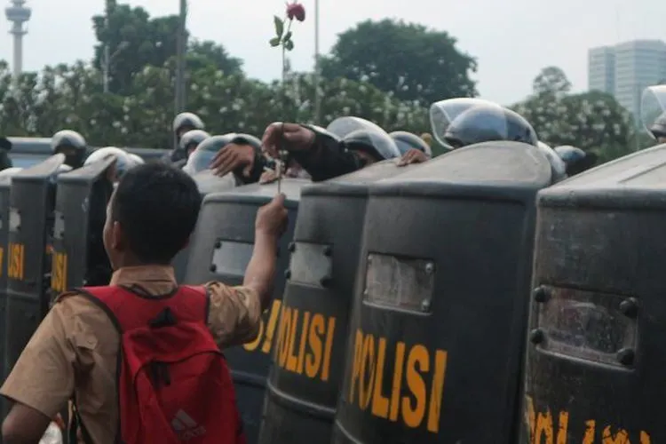 Seorang pelajar memberikan setangkai bunga untuk aparat kepolisian di seberang Gedung DPR RI, Jakarta, Rabu (25/9/2019)/Antara